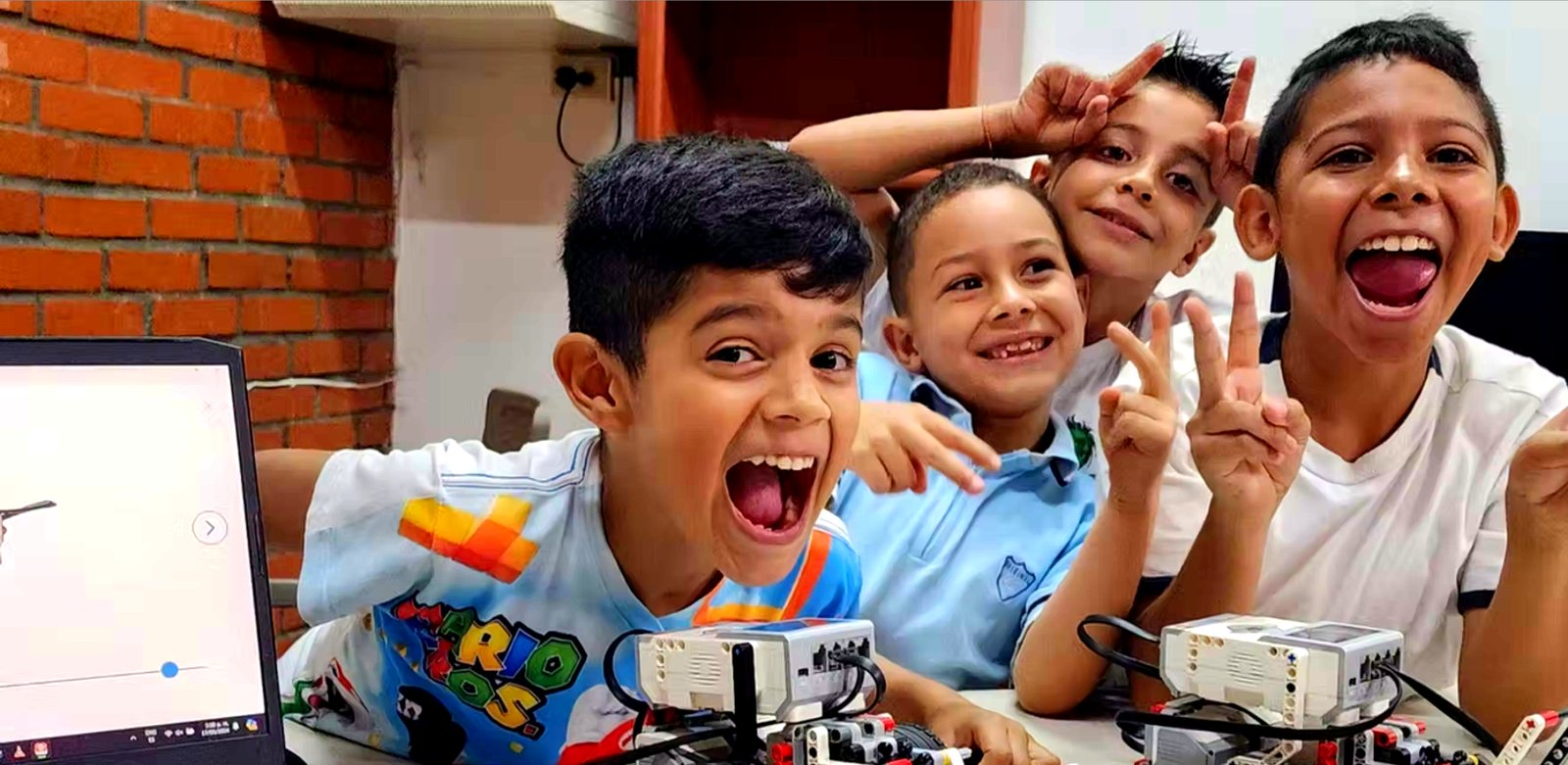 Tres estudiantes del club celebran frente a sus robots Lego EV3, con un portátil al lado