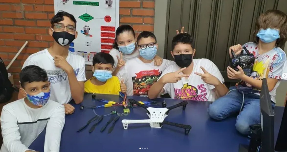 Siete estudiantes con tapabocas alrededor del chasis de un dron