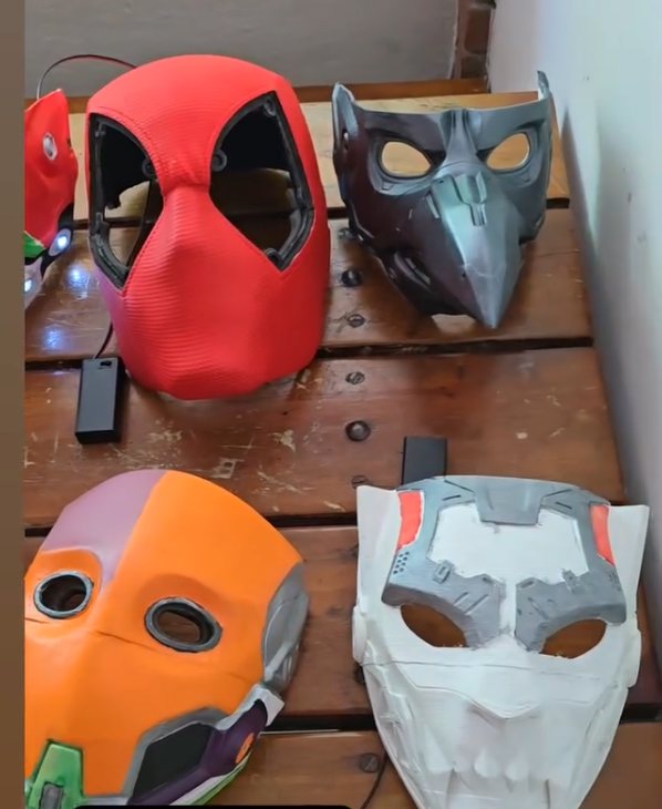 Cuatro máscaras más: una roja de tela, una gris de pico, una naranja y morada, y una blanca con mandíbula