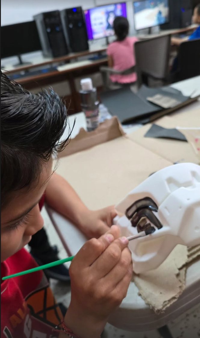Un estudiante pinta con pincel los detalles de su máscara blanca impresa en 3D