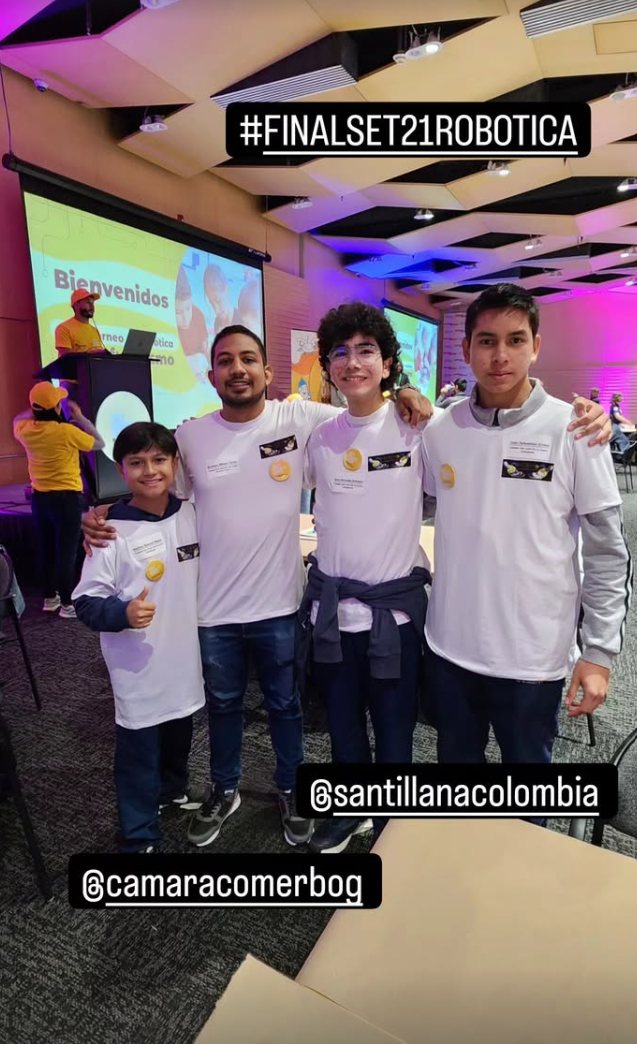 El equipo de tres estudiantes con su docente en el auditorio de la final, con las camisetas del torneo