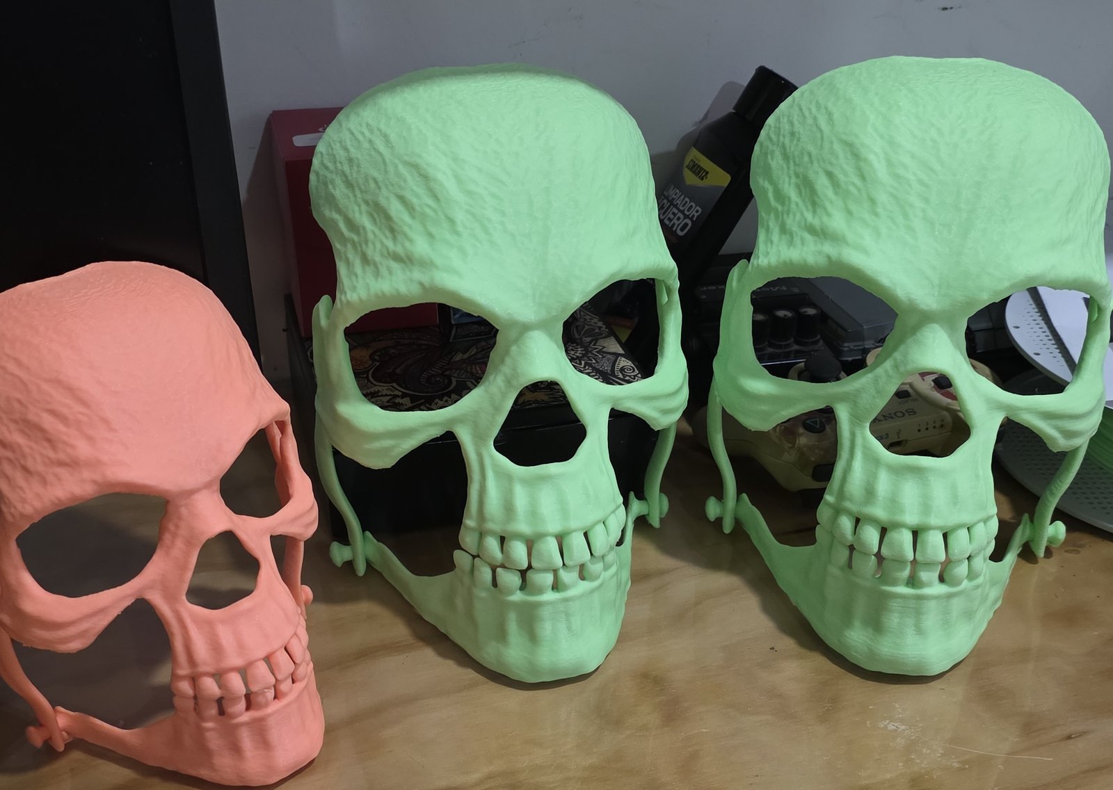 Tres máscaras de calavera impresas en 3D con mandíbula articulada, una coral y dos verdes fluorescentes
