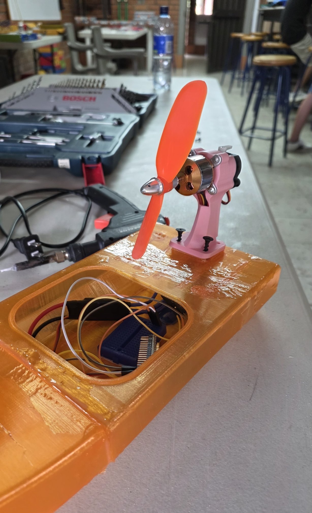 Casco naranja impreso en 3D con el soporte del motor, el motor brushless y la hélice montados, y la electrónica dentro