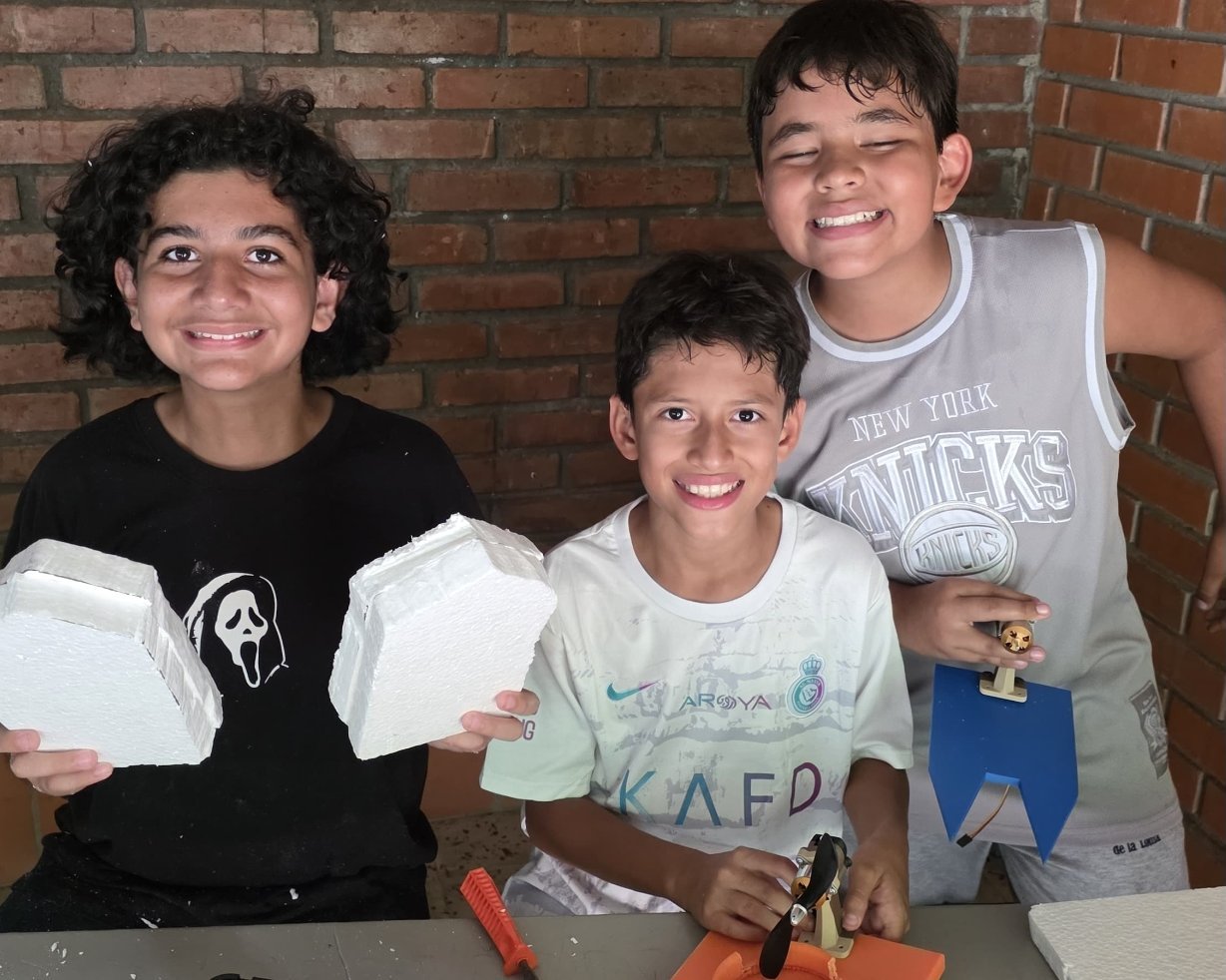 Tres estudiantes con los flotadores, el casco impreso en 3D y la hélice de su lancha