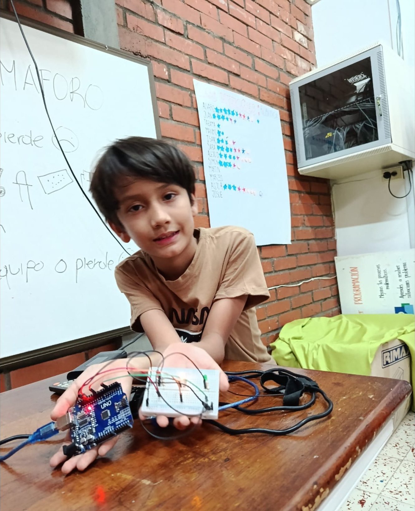 Un estudiante muestra su semáforo armado con Arduino y una protoboard